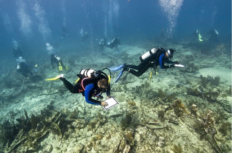 Scuba divers in full gear assessing a shipwreck in the Florida Keys