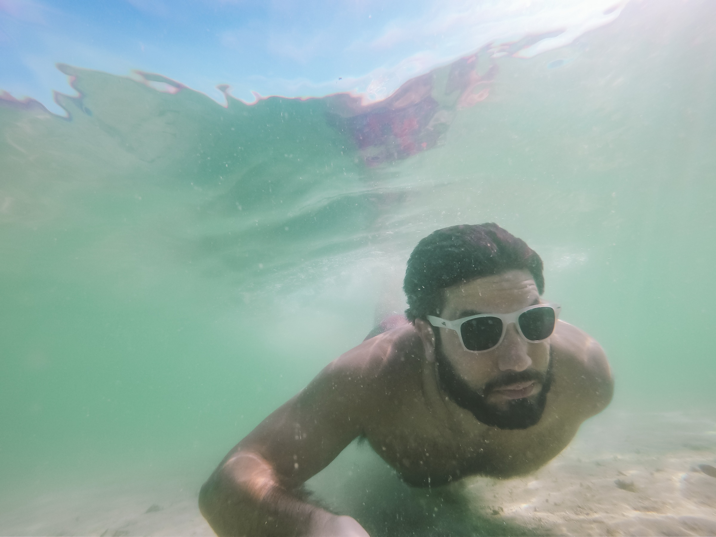 A freediver gliding underwater in clear blue open-ocean water