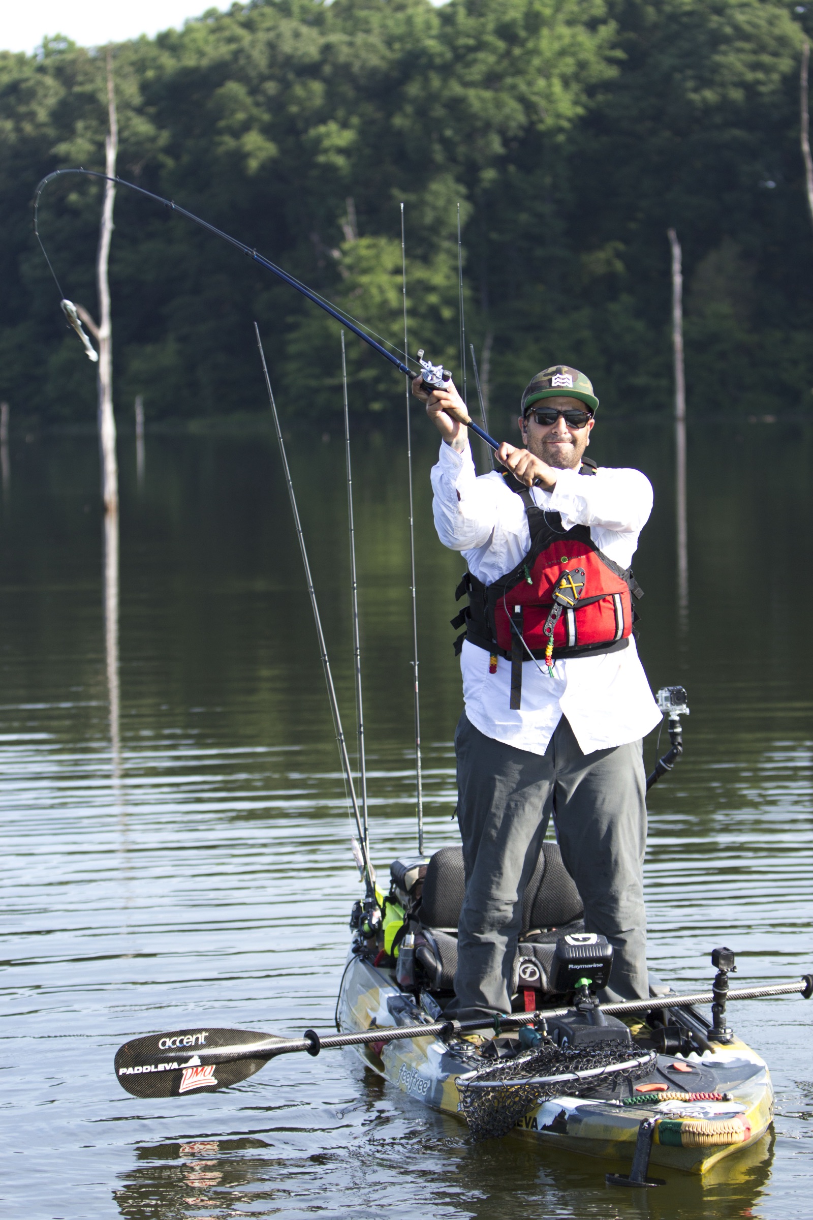 A person in a life vest fighting a fish from a fully rigged fishing kayak