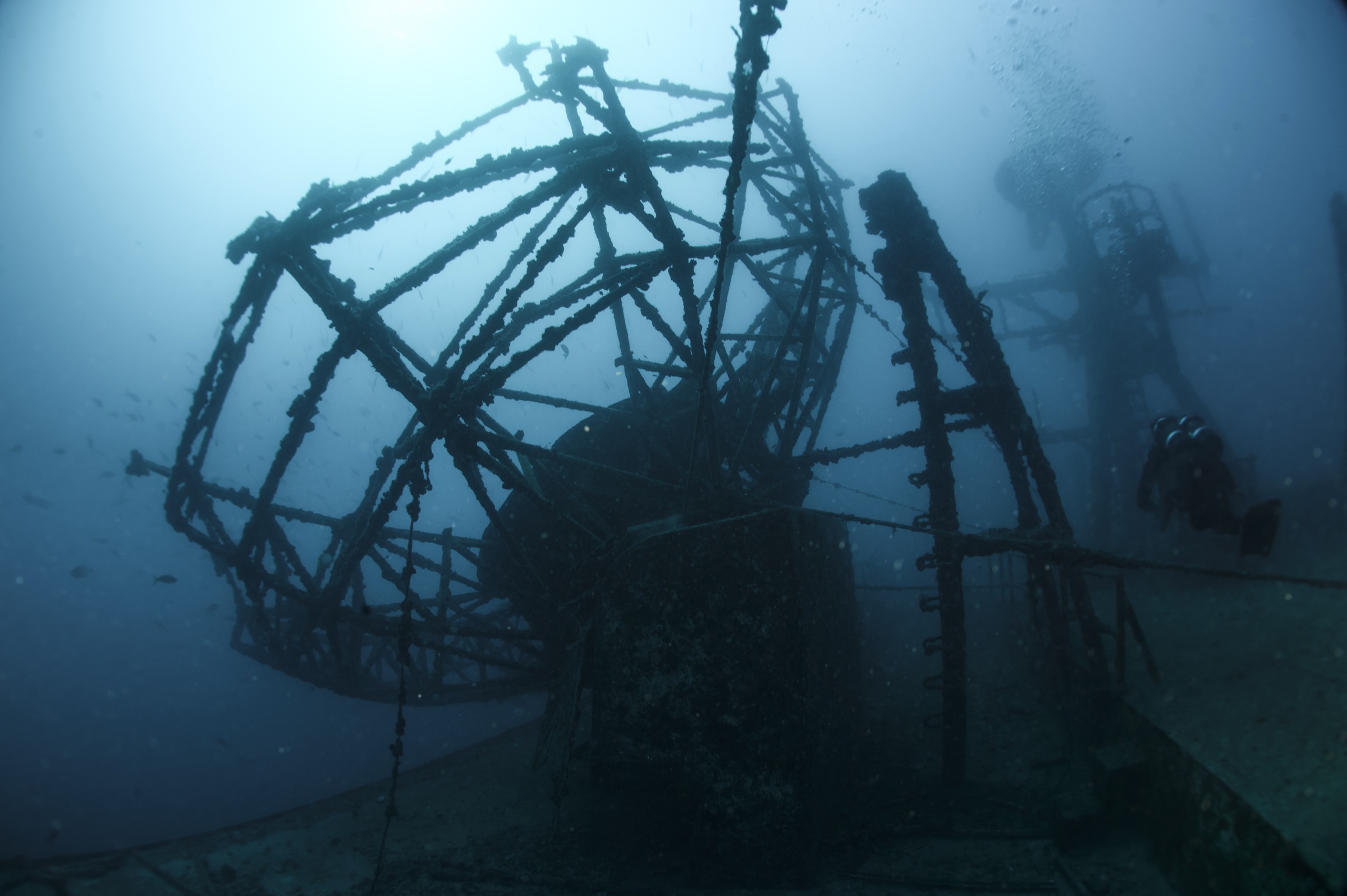Scuba diver in full gear examining the deteriorated metal hull of the intentionally sunk USNS General Hoyt S. Vandenberg wreck underwater off the Florida coast