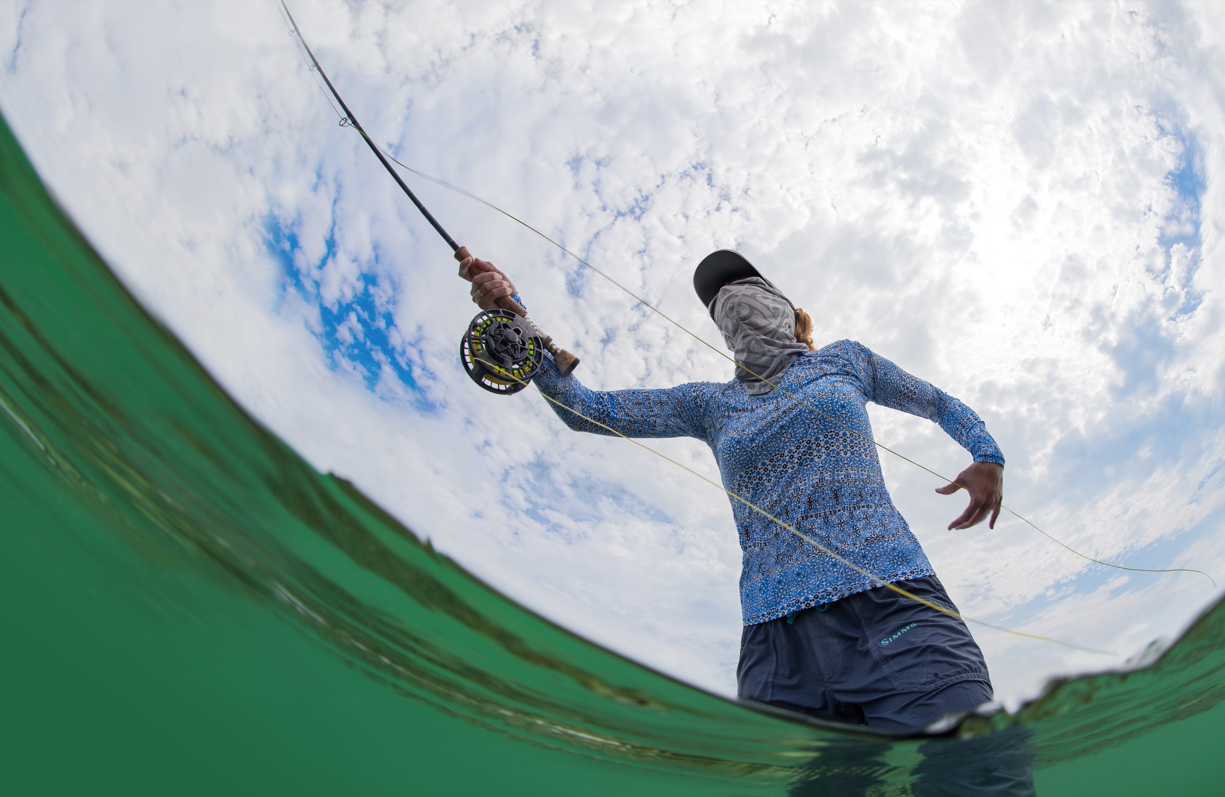 An angler fly fishing in the shallow salt flats of the Florida Keys, wading through calm turquoise water under open sky